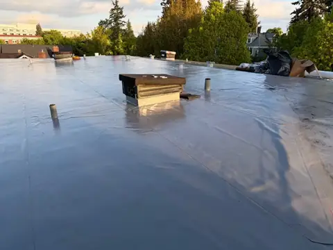 Completed dark low-slope roof membrane with sealed penetrations